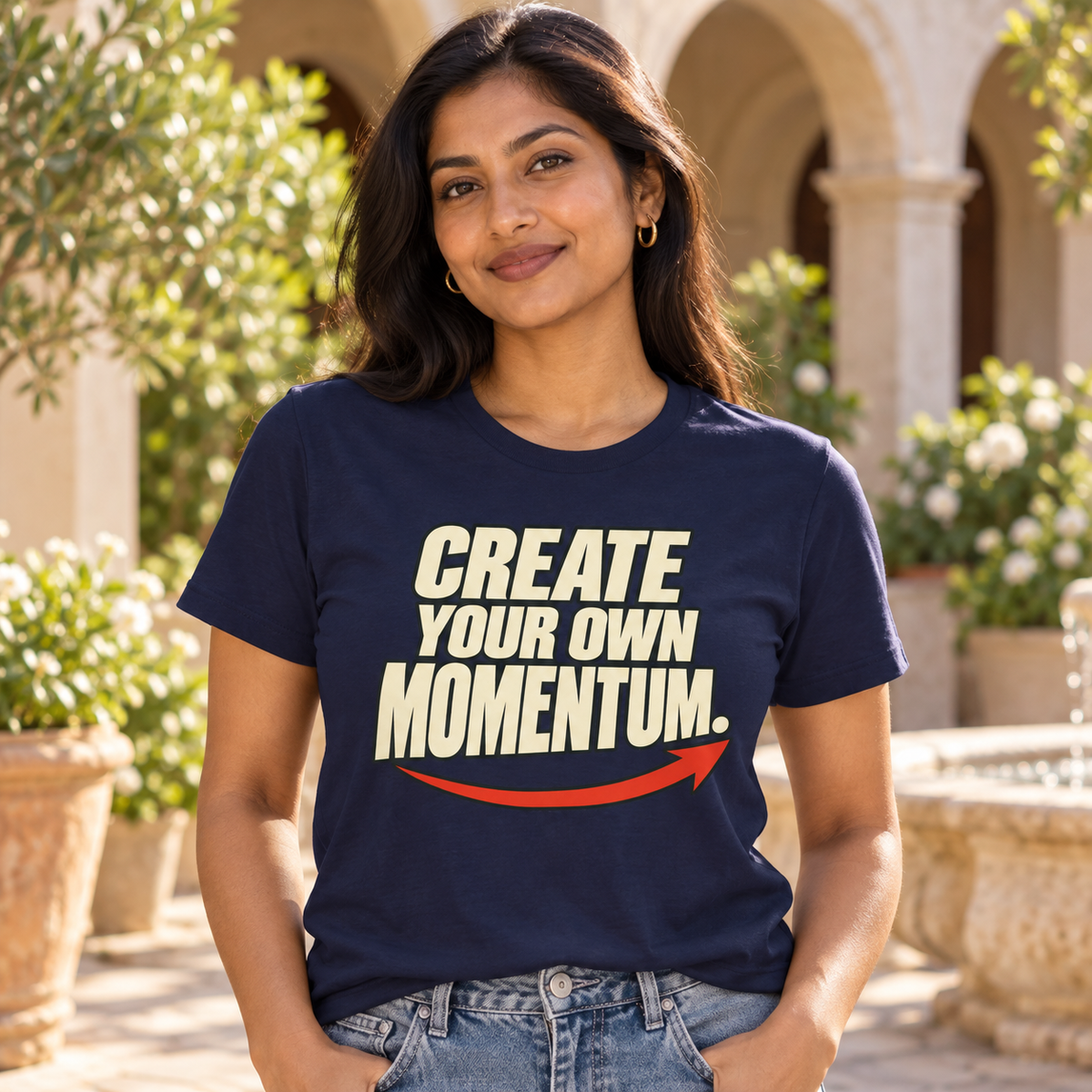 Woman wearing the Create Your Own Momentum. navy T-shirt in a sunny courtyard